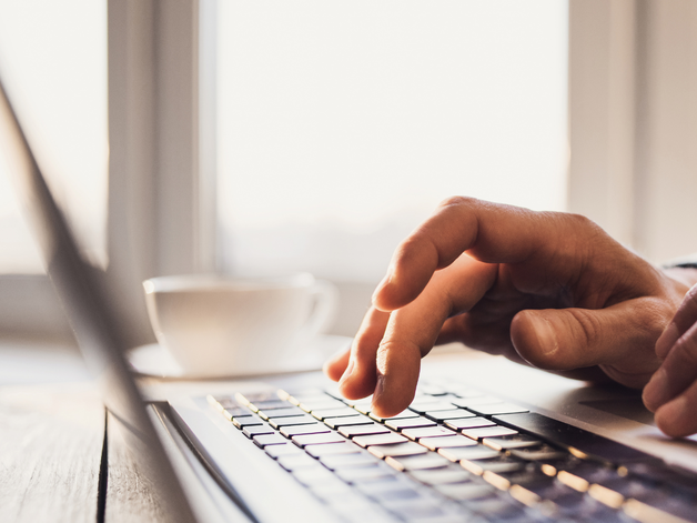 Close up image of hands typing on a laptop keyboard