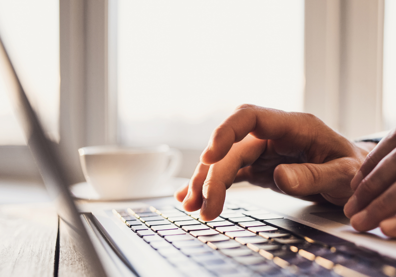 Close up image of hands typing on a laptop keyboard